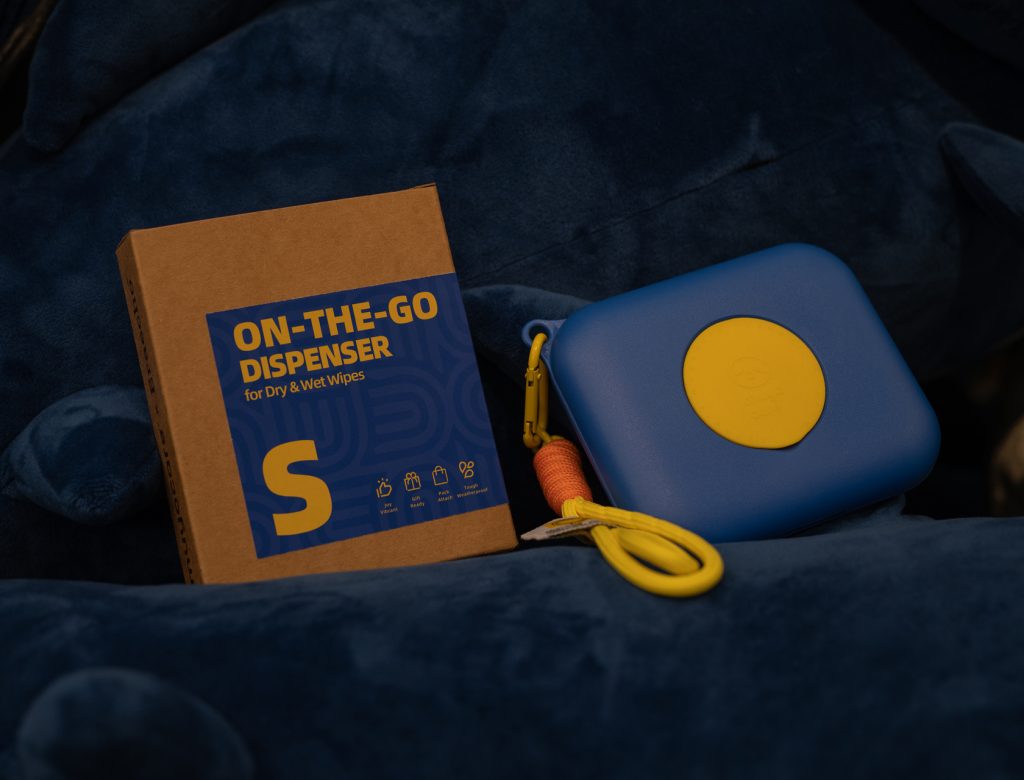 Portable blue case with yellow button, ideal for carrying wet wipes during travel.