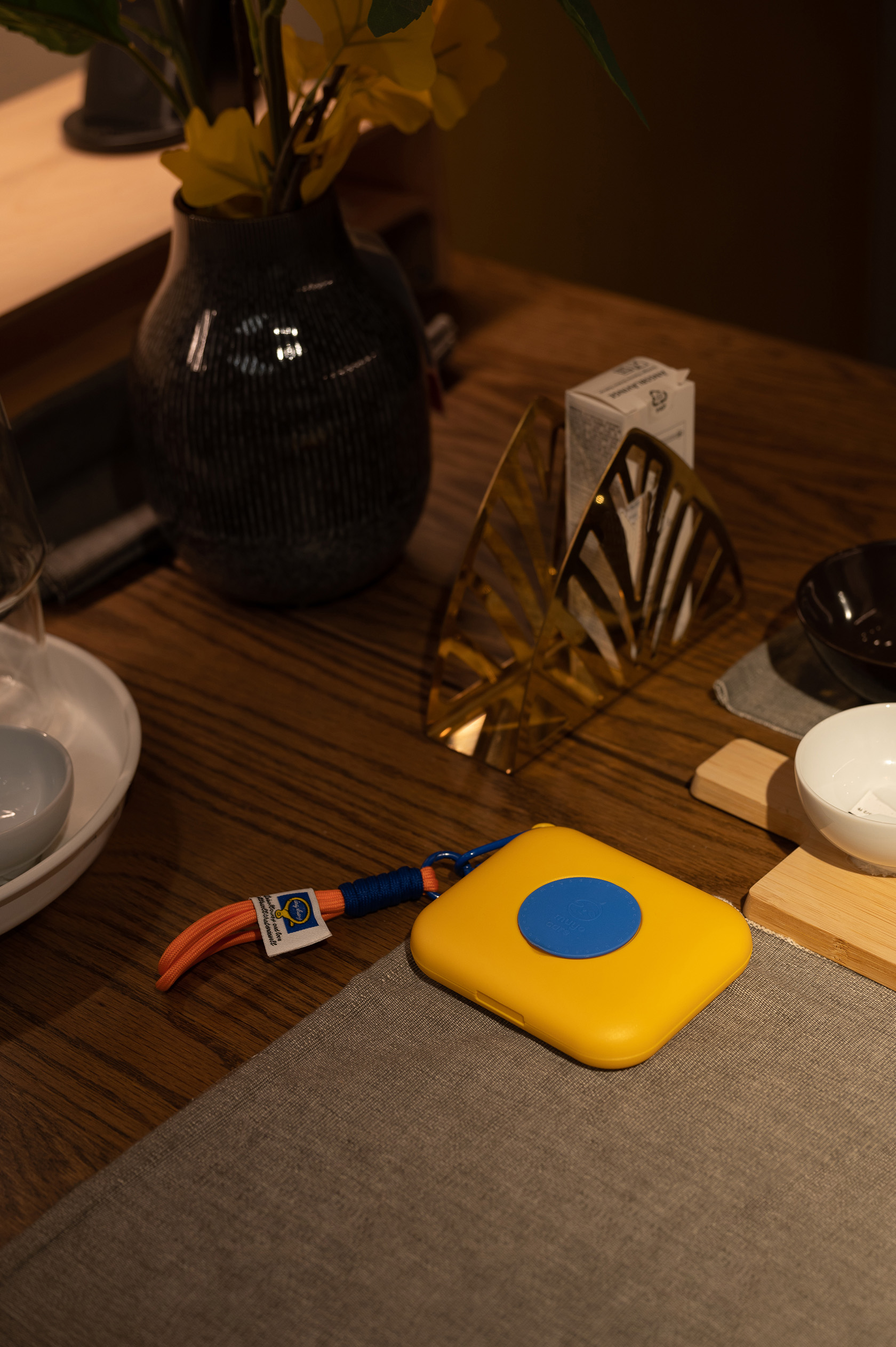 Image shows a yellow portable AED (Automated External Defibrillator) on a dining table, ready for emergency use.