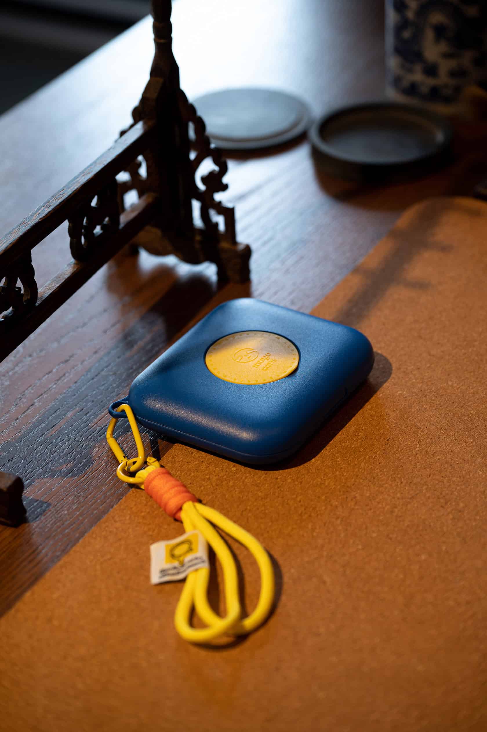 Compact blue first aid kit with yellow strap on wooden table, ideal for emergency preparedness.