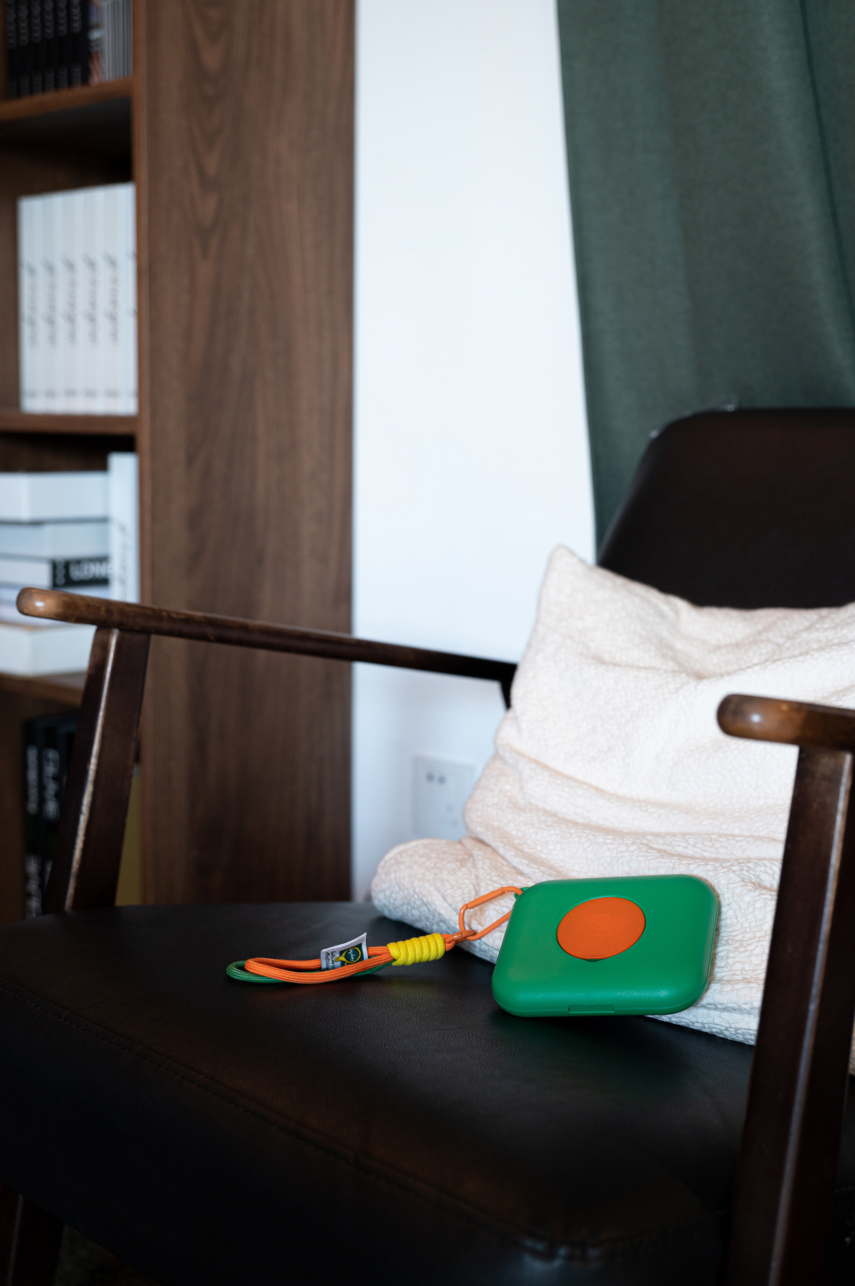 Compact medical gadget with lanyard on chair for health monitoring.