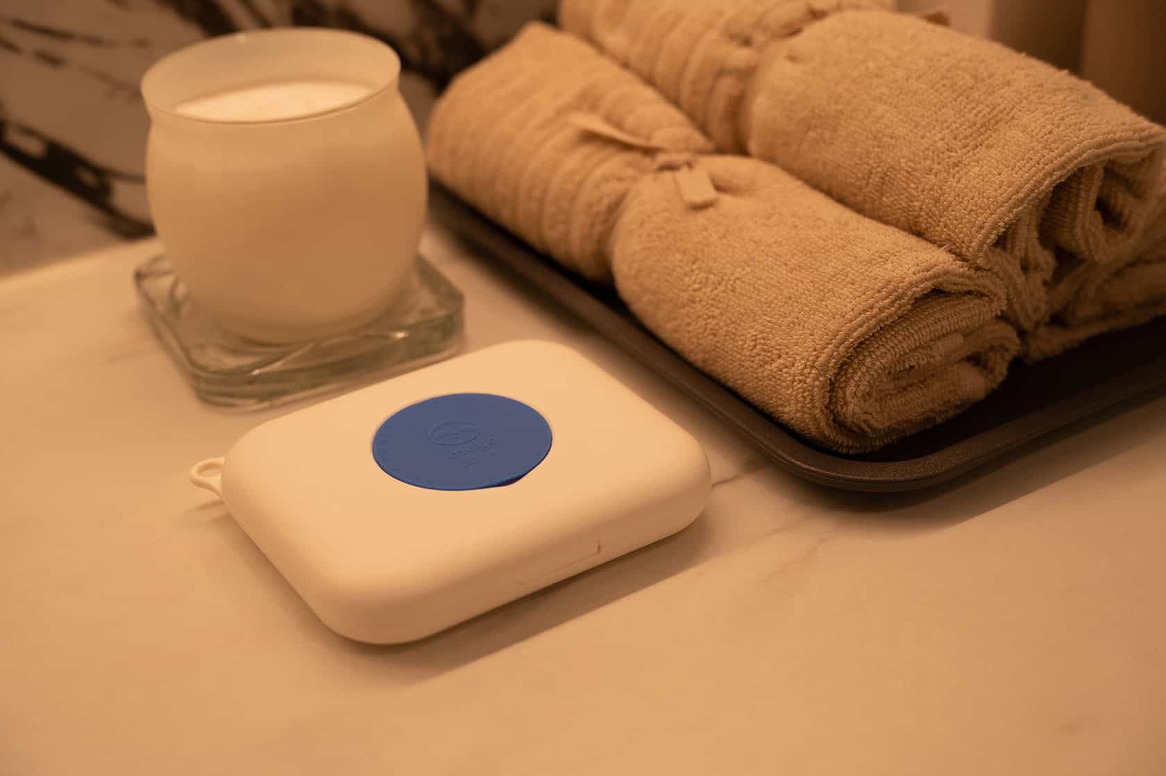 Compact wellness device and cozy towels in spa setting for relaxation and self-care.